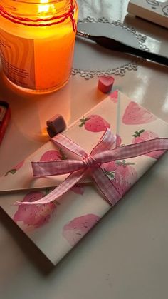 a candle is lit next to a wrapped gift on a table with other items around it