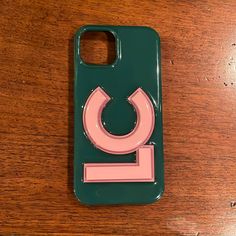 a cell phone case with a pink and green design on the back, sitting on a wooden table