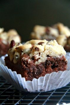 chocolate cupcakes sitting on top of a cooling rack with muffins in the background