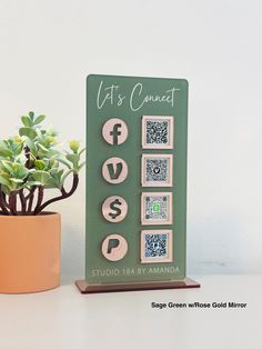 a small potted plant next to a wooden sign with qr code stamps on it