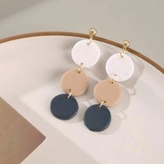 three different colored disc earrings on top of a white plate with a brown and black circle