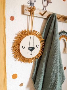 a towel hanging on the wall next to a coat rack with a sun face decoration