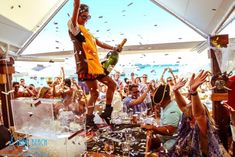 a man is standing on top of a table while people are throwing confetti in the air