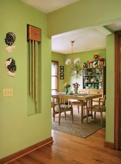 a dining room with green walls and wooden floors