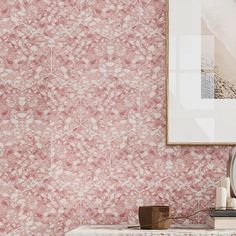 a pink wallpapered room with a clock and other items on the table next to it