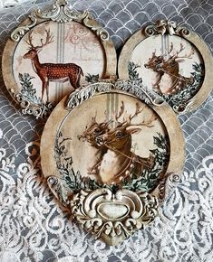 three plates with deer on them sitting on a lace tablecloth