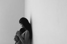 black and white photograph of a woman leaning against a wall