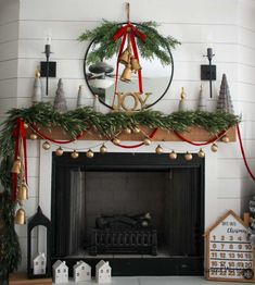 a mantel decorated for christmas with greenery and bells