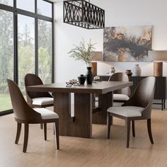 a dining room table and chairs in front of large windows