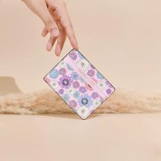 a hand reaching for a pink and blue flowered wallet on top of a pile of fur