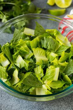 lettuce in a glass bowl next to lemon wedges