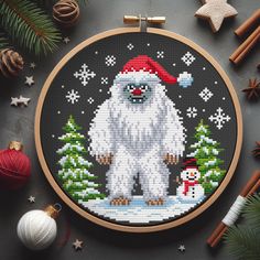 a cross stitch christmas ornament with a polar bear and snowman