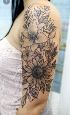 a woman's arm with flowers and leaves tattooed on the back of her shoulder