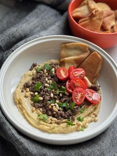 a white plate topped with hummus, beans and tomatoes