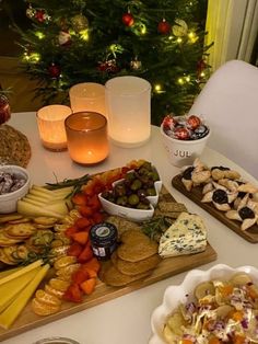 an assortment of cheeses, crackers and other snacks on a table next to a christmas tree