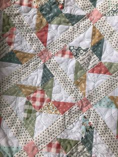 a close up view of a quilt on a table cloth with polka dots and triangles