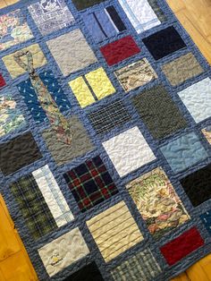 a quilted table topper with many different colors and designs on it, sitting on a wooden floor