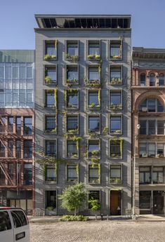 an apartment building with many windows and plants growing on the side of it's facade