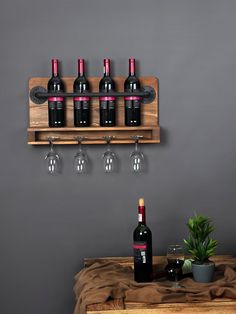 wine glasses and bottles are sitting on a wooden shelf next to a potted plant