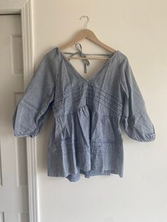 This soft denim shirt is cute! It has a tie at the top of the back and a deep V in both the front and back.  Size large Casual Light Wash V-neck Top, Summer V-neck Washed Tops, Chic Spring Denim V-neck Top, Chic V-neck Denim Top For Spring, Spring V-neck Blouse With Tie Back, Trendy Denim V-neck Top, Summer Cotton Blouse With Tie Back, Summer Cotton Tie Back Blouse, Spring Cotton Blouse For Brunch