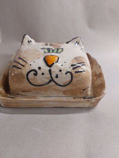 a ceramic cat sitting on top of a wooden tray