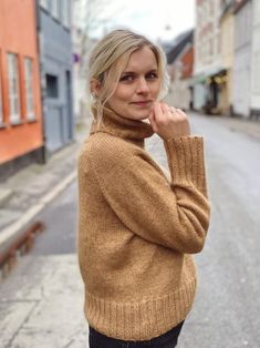 a woman standing in the middle of an empty street with her hand on her chin