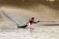 a woman is water skiing in the lake while being pulled by a boat behind her