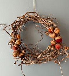 a wreath made out of twigs and acorns hangs on the wall next to a door