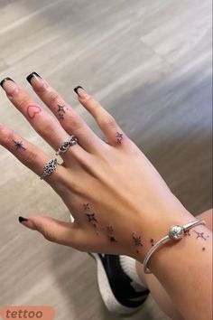 a woman's hand with stars and moon tattoos on it