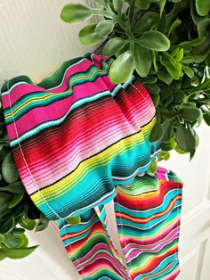 a colorful towel hanging on the side of a door next to a potted plant