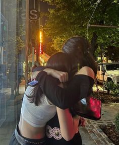 two women hugging each other on the sidewalk