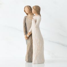 two figurines standing next to each other on a white surface with one holding the other's hand