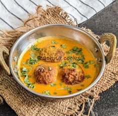 a metal bowl filled with meatballs and curry