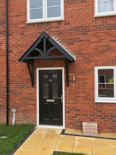 a black front door on a red brick building with white windows and an awning