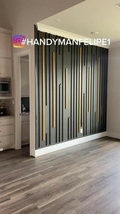 an empty living room with wood floors and white cabinets in front of a black paneled wall