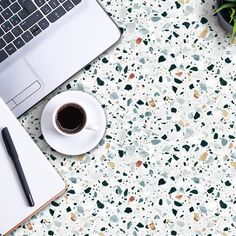 an open laptop computer sitting on top of a desk next to a cup of coffee