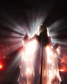 a woman with long hair standing in front of a microphone on stage at a concert