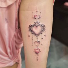 a woman's leg with a heart tattoo on it and two hearts hanging from the side