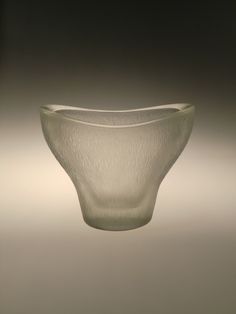 a white glass bowl sitting on top of a gray table next to a black wall