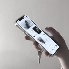 a person holding a smart phone in their hand with keys attached to the back of it