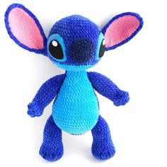 a blue stuffed animal with pink ears and big eyes on a white background that appears to be crocheted