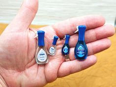 a hand holding three small blue and white bottles in it's palm, next to a bottle opener