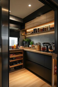 a kitchen with wooden flooring and black cabinetry is seen through an open door