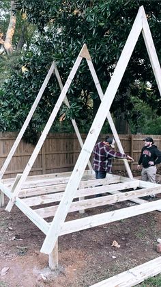 two men are building a wooden structure in the yard