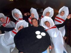 a group of people dressed in costumes and holding up a black object with white circles on it