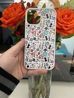 a person holding up a phone case with flowers in the background