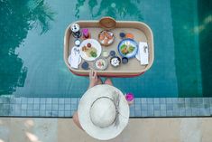 an overhead view of a person holding a tray with food on it next to a swimming pool