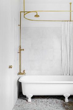 a white bath tub sitting in a bathroom next to a shower head and hand rail