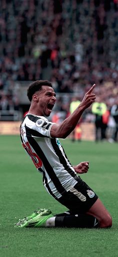 a soccer player sitting on the ground with his mouth open and hands in the air