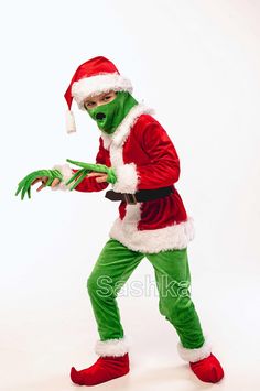 a man dressed as santa claus holding something in his hand while wearing green and red clothing